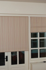 Photo showing a roller blind made up in a customer's own red and beige striped fabric which matches roman blinds in the same room